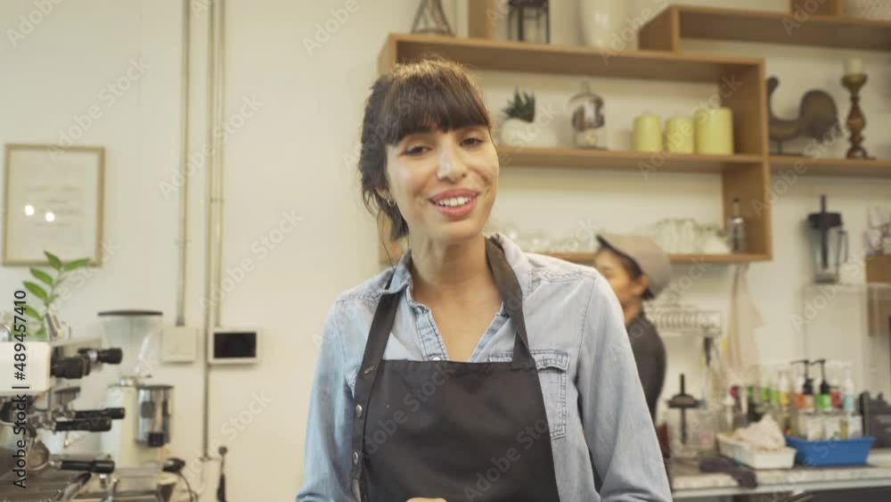Portrait of Asian woman barista people in apron selling products online via live e-commerce live or conference sales social media, cafe restaurant cashier. waitress in coffee shop. People lifestyle. Portrait of Asian woman barista people in apron selling products online via live e-commerce live or conference sales social media, cafe restaurant cashier. waitress in coffee shop. People lifestyle.