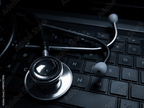 Low key photo of stethoscope on keyboard. Health and technology concept.