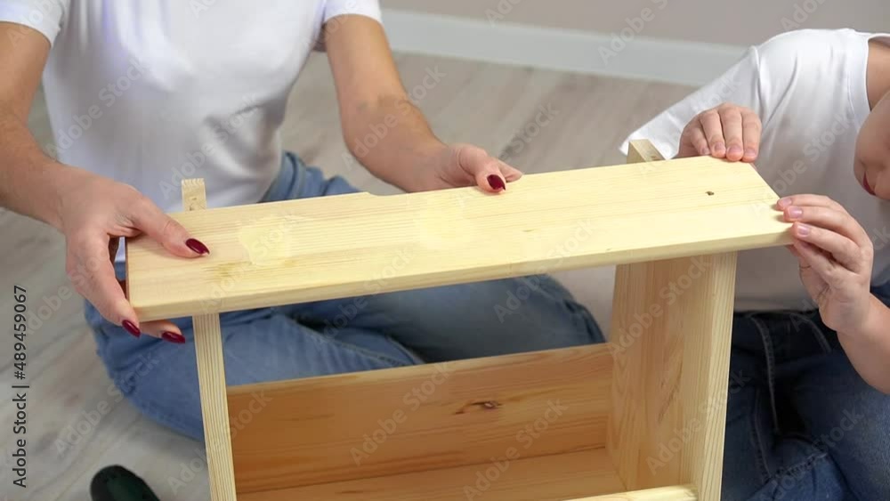 Happy family mother and daughter assembling wooden furniture together. DIY concept Happy family mother and daughter assembling wooden furniture together. DIY concept