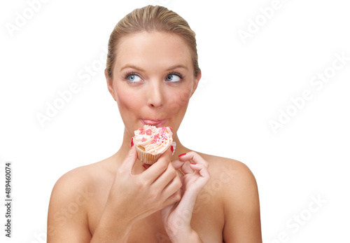 Stealing a bit of sweetness. A naughty looking blonde woman eating a cupcake.
