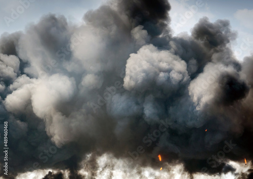 plumes of black smoke replace a blue sky after a huge explosian photo