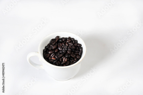 white cup with roasted coffee beans isolated with copy space