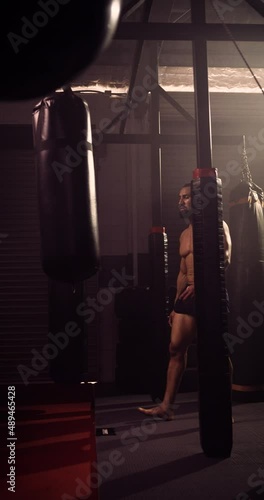 A Vertical Video Of A Hispanic Bodybuilder Boxing In An MMA Gym. Shot In A Crossfit Boxing Gym With Low Key Lighting And A Scattering Of Haze. Captured On Red Digital Cinema Camera 