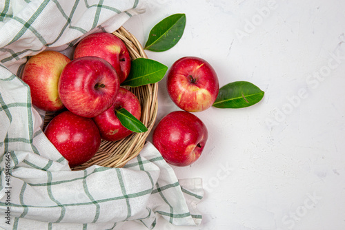 Happy red apples in a sweet basket on a white table. Art style, the top view has space for your messages.