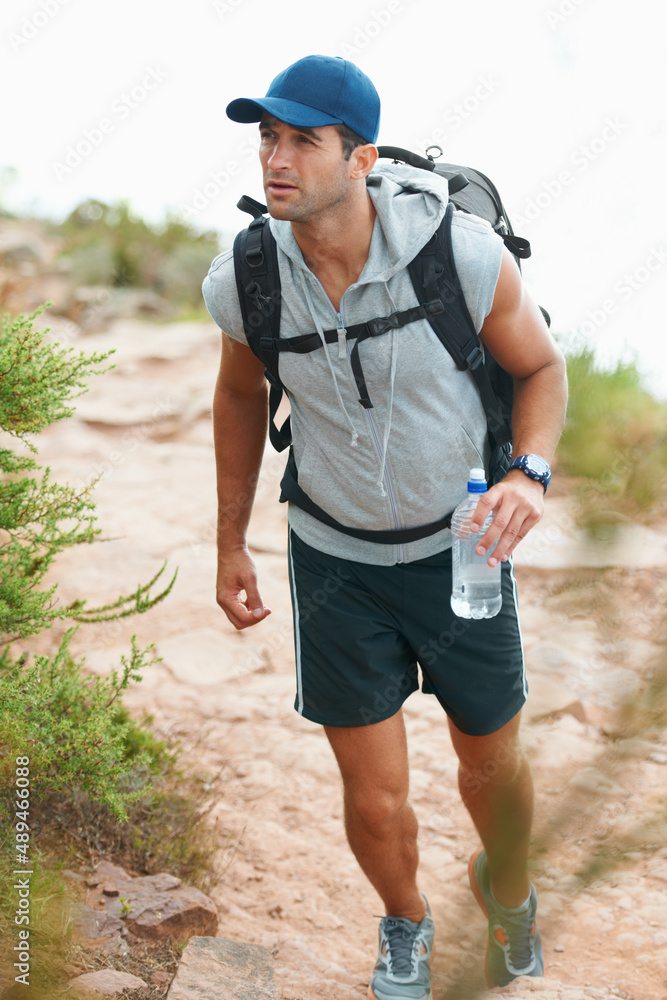 Its important to keep hydrated. Happy young hiker walking with a bottle of water in his hand. Its important to keep hydrated. Happy young hiker walking with a bottle of water in his hand.