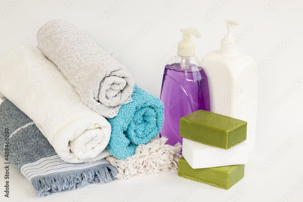 Rolled up multi color bath and face towels on white background with natural olive oil soaps and liquid soap Rolled up multi color bath and face towels on white background with natural olive oil soaps and liquid soap