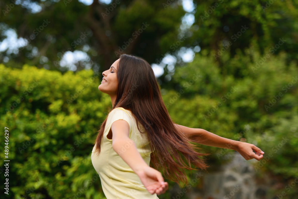 Completely free. Shot of a woman enjoying the outdoors with her arms raised. Completely free. Shot of a woman enjoying the outdoors with her arms raised.