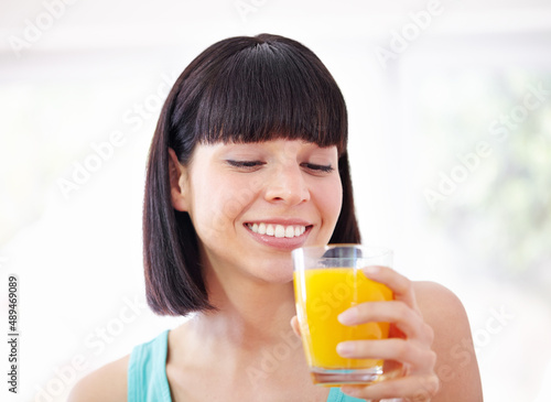 Enjoying a glass of juicy goodness. A young woman drinking orange juice.