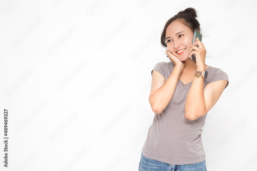 Beautiful Asian woman wearing grey casual shirt holding smartphone on white background and copy space. Cute Asian woman smiling and cheerful talk something on the phone for social media concept Beautiful Asian woman wearing grey casual shirt holding smartphone on white background and copy space. Cute Asian woman smiling and cheerful talk something on the phone for social media concept