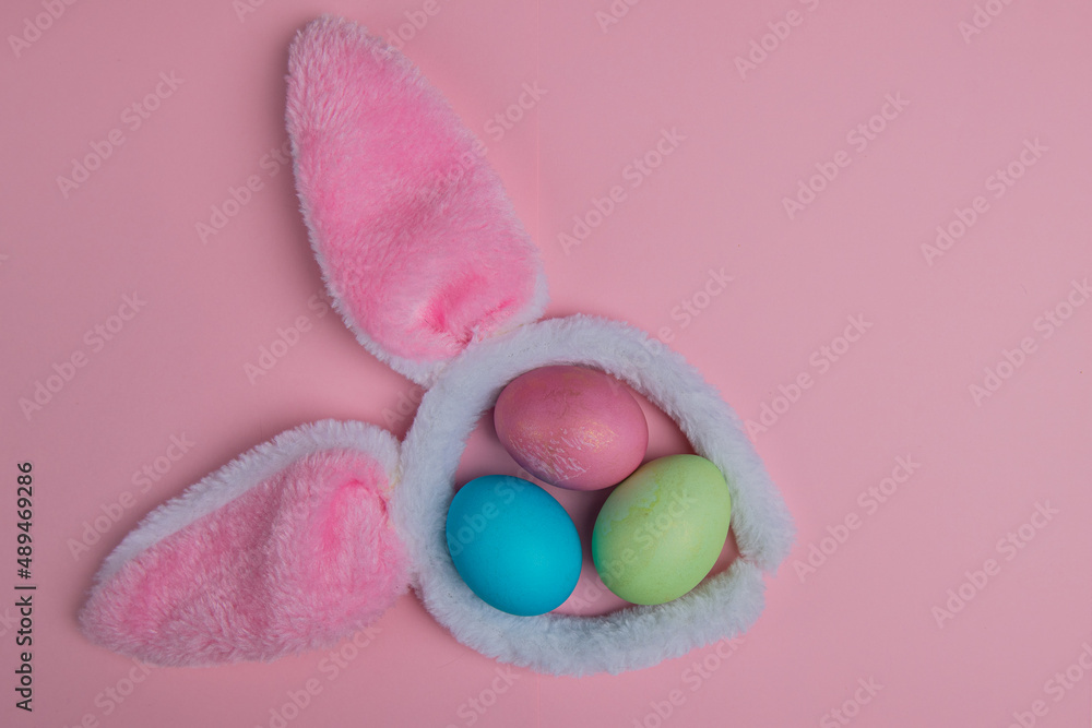bunny ears on a pink background and three easter eggs