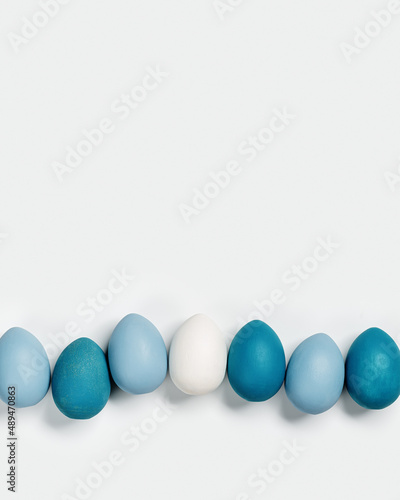 Painted Easter eggs blue, gray colored in row on white background with copy space. Chicken egg natural pastel shades. Easter holiday food, minimal design aesthetic flat lay