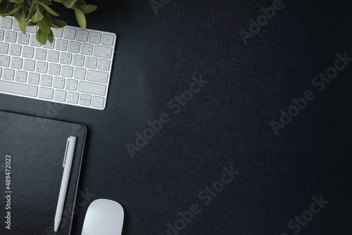 top view working desk with keyboard mouse and notebook on black table background