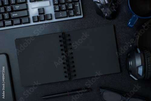 top view working desk with keyboard headphone and open notebook on black table background