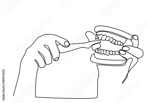 a dentist doctor demonstrates how to clean dentures with a toothbrush