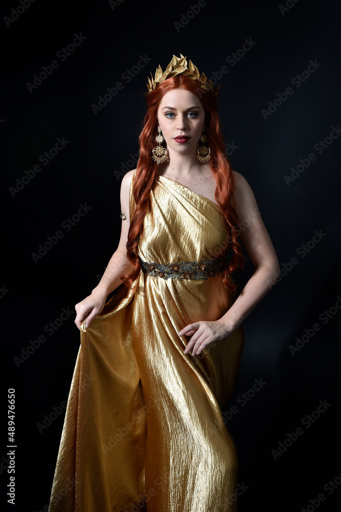 Full length portrait of pretty female model wearing grecian goddess toga gown, posing with elegant gestural movements on a studio background. Full length portrait of pretty female model wearing grecian goddess toga gown, posing with elegant gestural movements on a studio background.