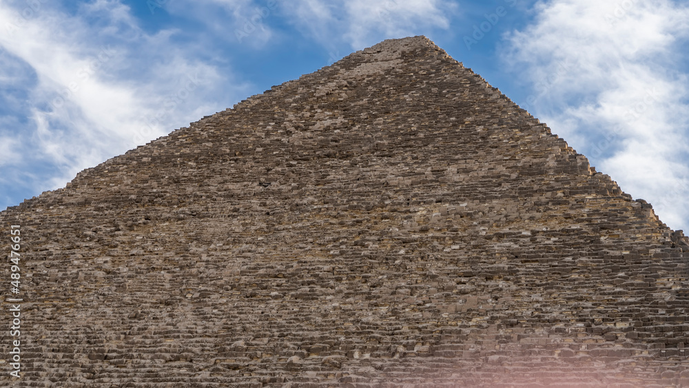 The Great pyramid of Cheops on a background of blue sky and clouds. The ancient masonry walls are visible. Close-up. Egypt. Giza