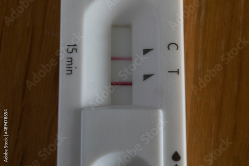Covid rapid antigen test showing positive result on wooden table. Horizontal format close up with selective focus