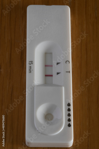 Foto Covid rapid antigen test showing positive result on wooden table
