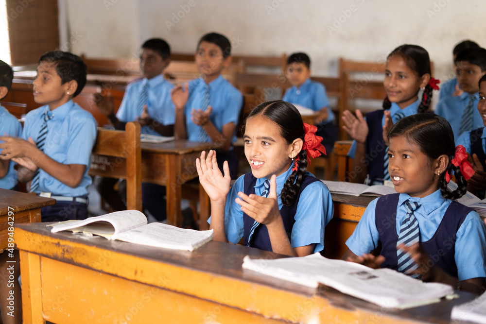 Focus on girl, young school kids in uniform applauding or clapping at classroom - concept of growth, entertainment, inspiration and childhood lifestyle. Focus on girl, young school kids in uniform applauding or clapping at classroom - concept of growth, entertainment, inspiration and childhood lifestyle.