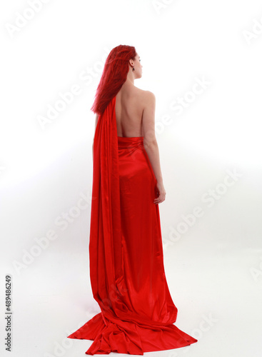 Full length portrait of red haired woman wearing a  beautiful sexy silk gown costume  standing pose with creative arm gestures  isolated on white studio background.