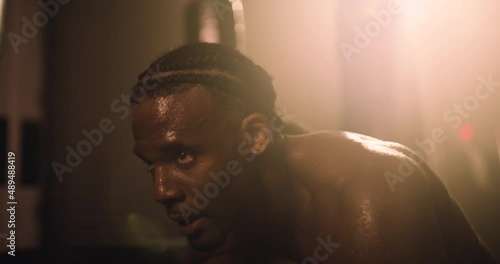 An African American Athlete Rests After An Intense Training Session. Shot In An MMA Boxing Gym With Low Key Lighting And A Scattering Of Haze. Captured On Red Digital Cinema Camera 