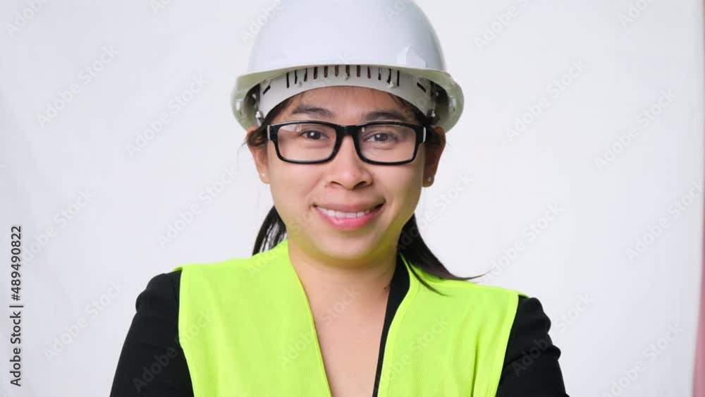 Smiling and confident female engineer wearing a helmet with her arms crossed over a white background in the studio. Smiling and confident female engineer wearing a helmet with her arms crossed over a white background in the studio.
