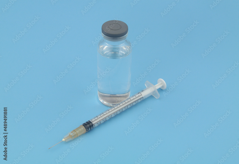 Vaccine bottle and syringe on blue background. Vaccination concept. Vaccine bottle and syringe on blue background. Vaccination concept.