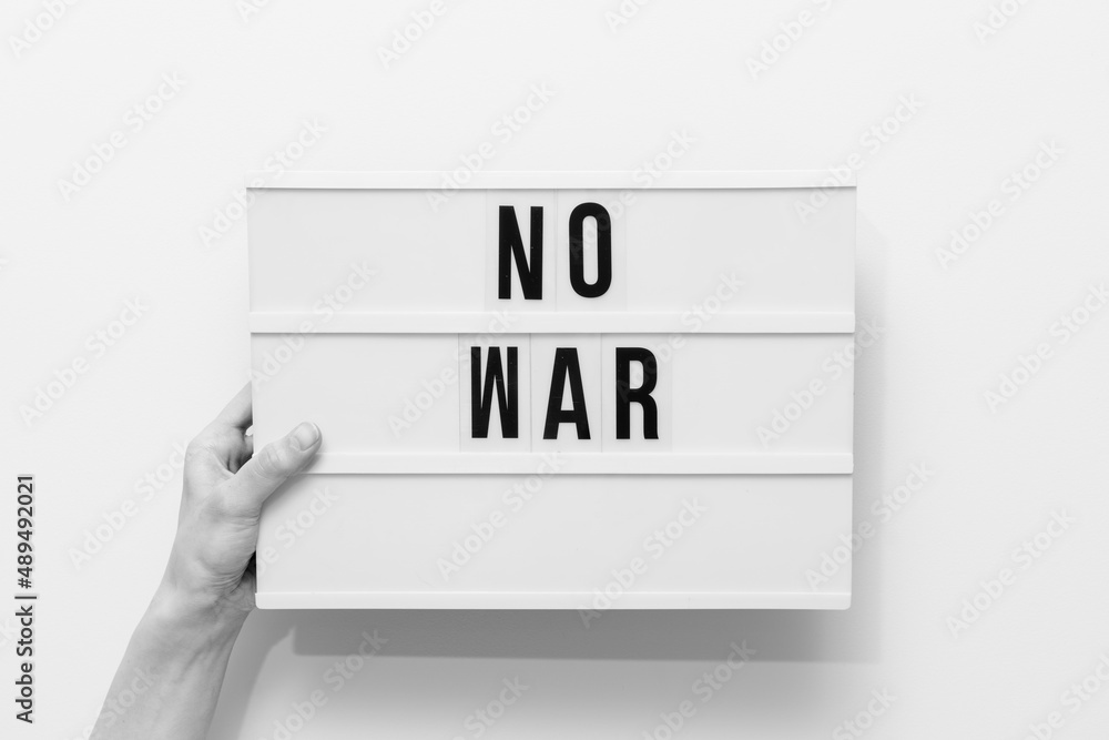 Hand holding a sign that says no to war Hand holding a sign that says no to war