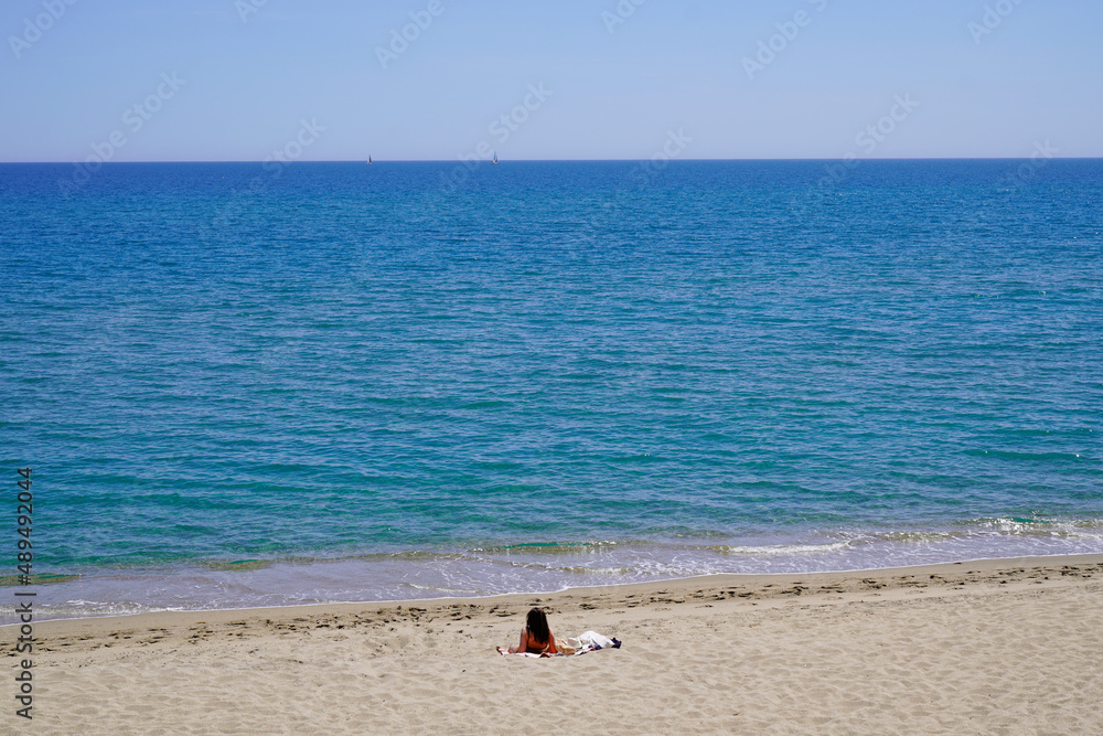 young and pretty woman lying relax on the fine sand of the beach alone in leucate france