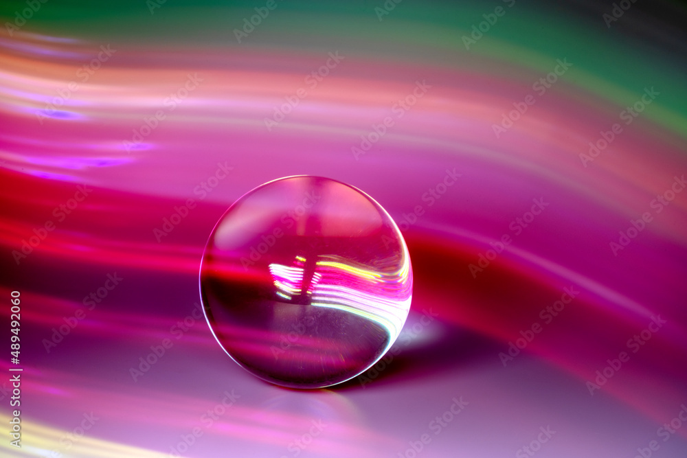 Glass ball and multicolored reflections on gray background Glass ball and multicolored reflections on gray background