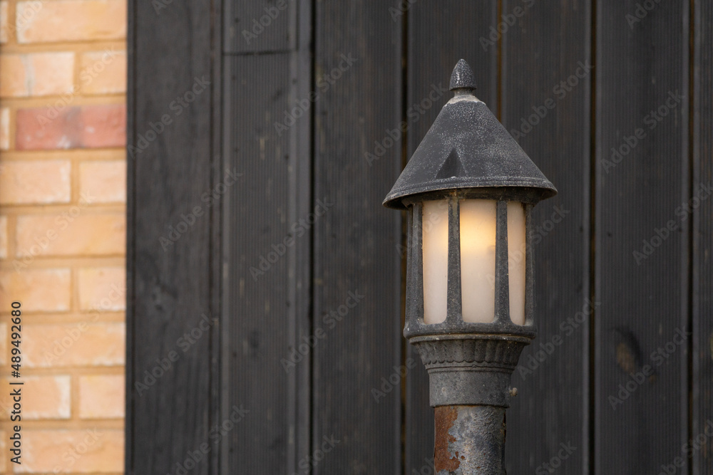 Street lamp installed in front of a wooden wall