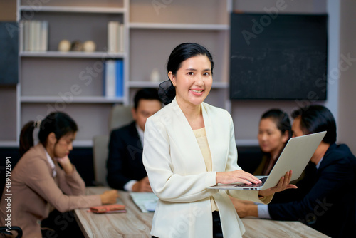 Asian smiling businesswoman hold laptop for portrait in meeting room