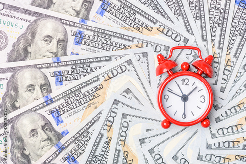 Time value of money concept : Red analog clock on US dollar banknote, depicting receiving money today can be poised to increase the future value by investing and gaining interest over a period of time