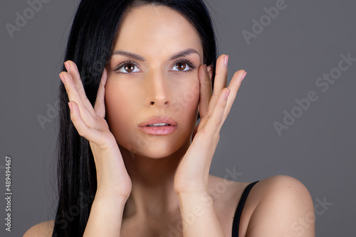Gorgeous, young woman with clean, fresh skin is touching own face. Cosmetology.