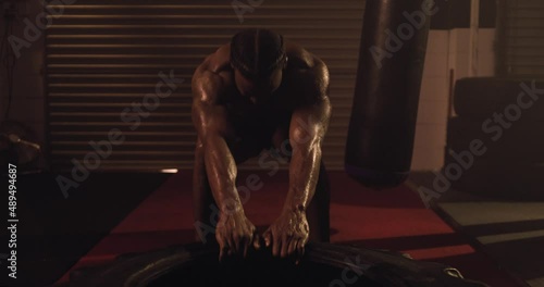 An African American Athlete Exercising, Tyre Pull In A Crossfit Gym. Shot In A MMA Boxing Gym With Low Key Lighting And A Scattering Of Haze. Captured On Red Digital Cinema Camera 