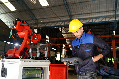 engineer checking control panel and teaching new Automatics robot arm and operating control machine in factory.
