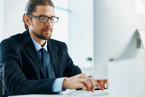 business man in a suit sitting at his desk tired in front of a computer