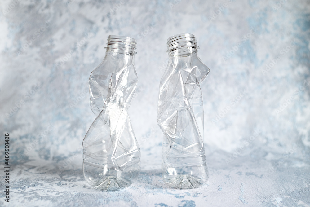 Two crushed empty plastic bottles prepared for recycling with caps and