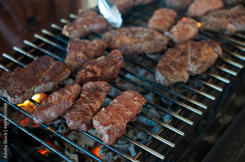 The cook prepares juicy steaks from marbled veal on grill The cook prepares juicy steaks from marbled veal on grill