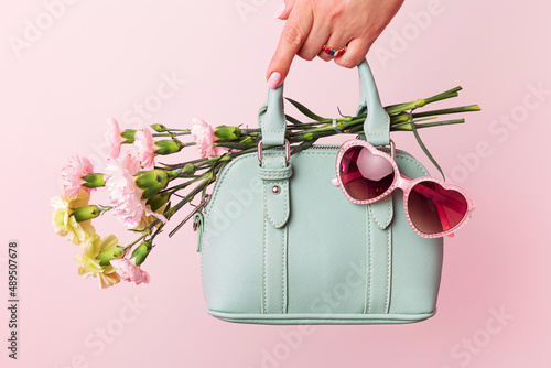 Fashion spring accessories - mint handbag (purse) and heart shaped sunglasses on pastel pink.