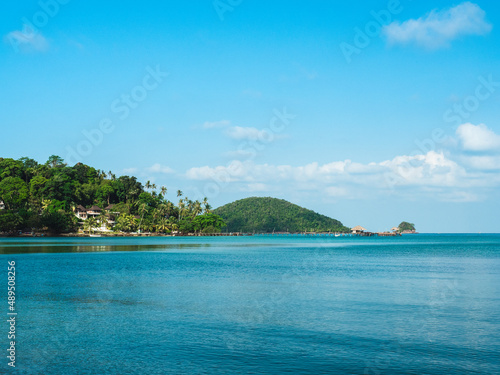 Scenic view of peaceful tropical island with long wooden pier landmark over turquoise sea water against blue sky. Koh Mak Island, Trat, Thailand. © Chavakorn