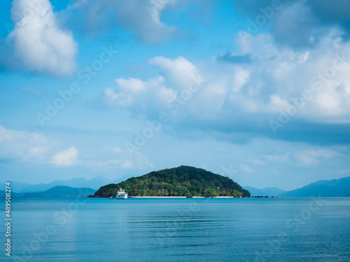 Scenic view of Koh Kham Island in the middle of peaceful bay against cloudy blue sky. Shot from Koh Mak Island, Trat, Thailand. Minimal background. © Chavakorn