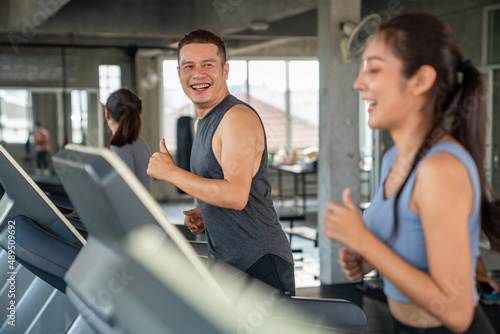 Group of Healthy Asian athletic man and woman in sportswear jogging workout exercise on treadmill together at fitness gym. Wellness male and female do sport training on running machine at sport club