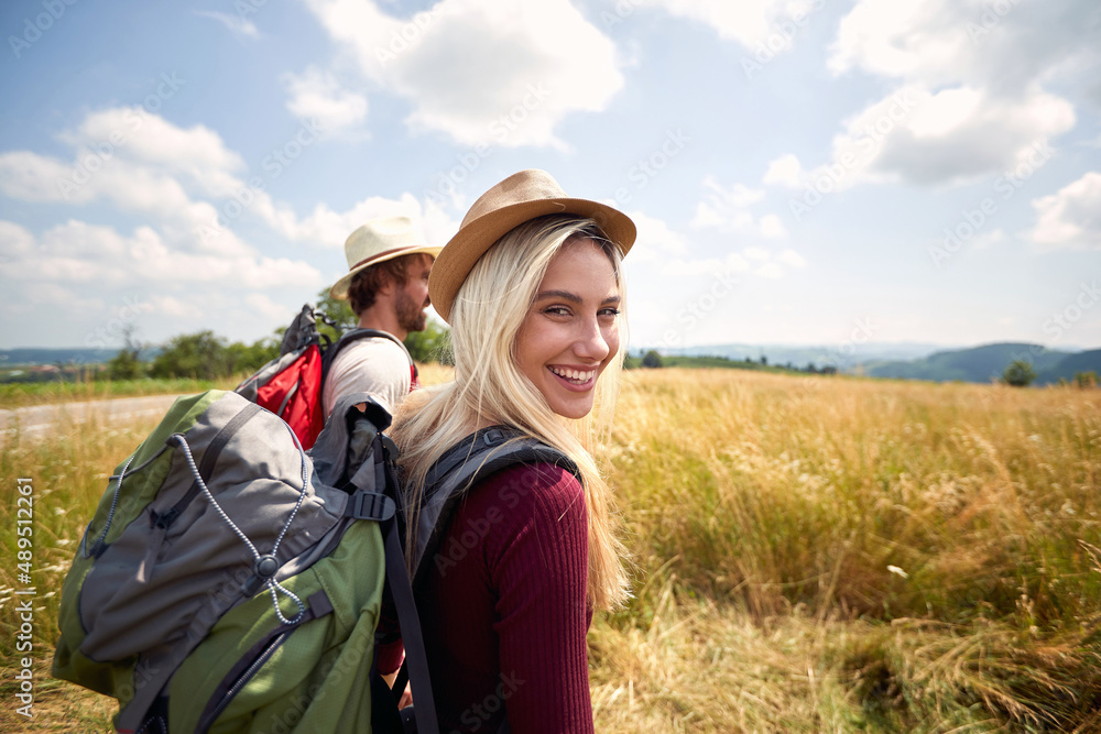 Hiker woman smilling and walking in field with a man, nature outdoor. Sport, freedom, holiday concept.
