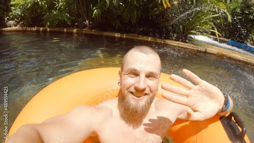 Young Happy Man Relaxing on Tube in Swimming Pool Lazy River in Waterpark. Happy Couple Having Fun in Waterpark. 4K Slowmotion Gopro Footage. Bali, Indonesia.