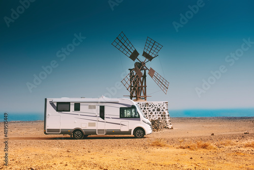 Foto Big modern camper van motorhome parked near an old windmille in the desert