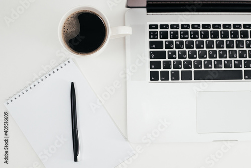 Office desk with laptop computer, notebook, pen and cup of coffee on white background