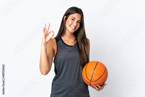 Young brazilian woman playing basketball isolated on white background showing ok sign with fingers © luismolinero