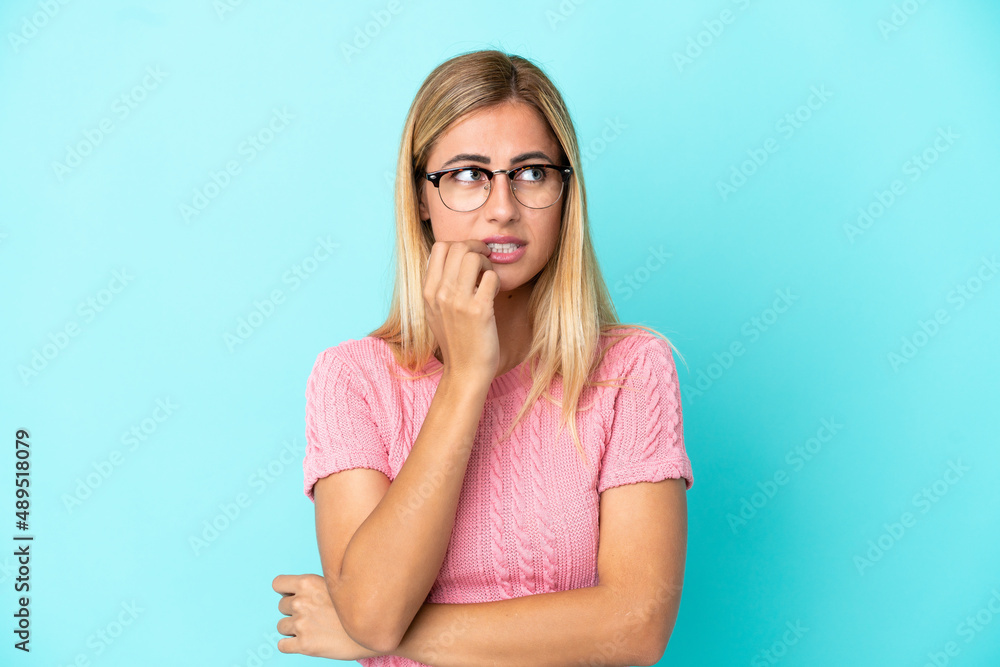 Blonde Uruguayan girl isolated on blue background nervous and scared Blonde Uruguayan girl isolated on blue background nervous and scared