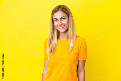 Blonde Uruguayan girl isolated on yellow background laughing